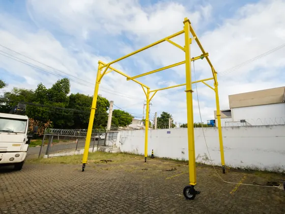 Pórtico móvel U amarelo com rodízios em pátio junto ao galpão