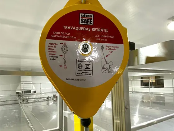 Trava-quedas retrátil amarelo instalado em área industrial